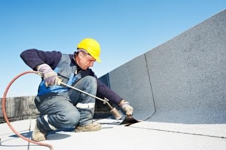 Workman using blowtorch on roof